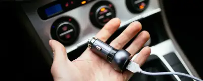 Зарядний кабель у руці біля автомобіля